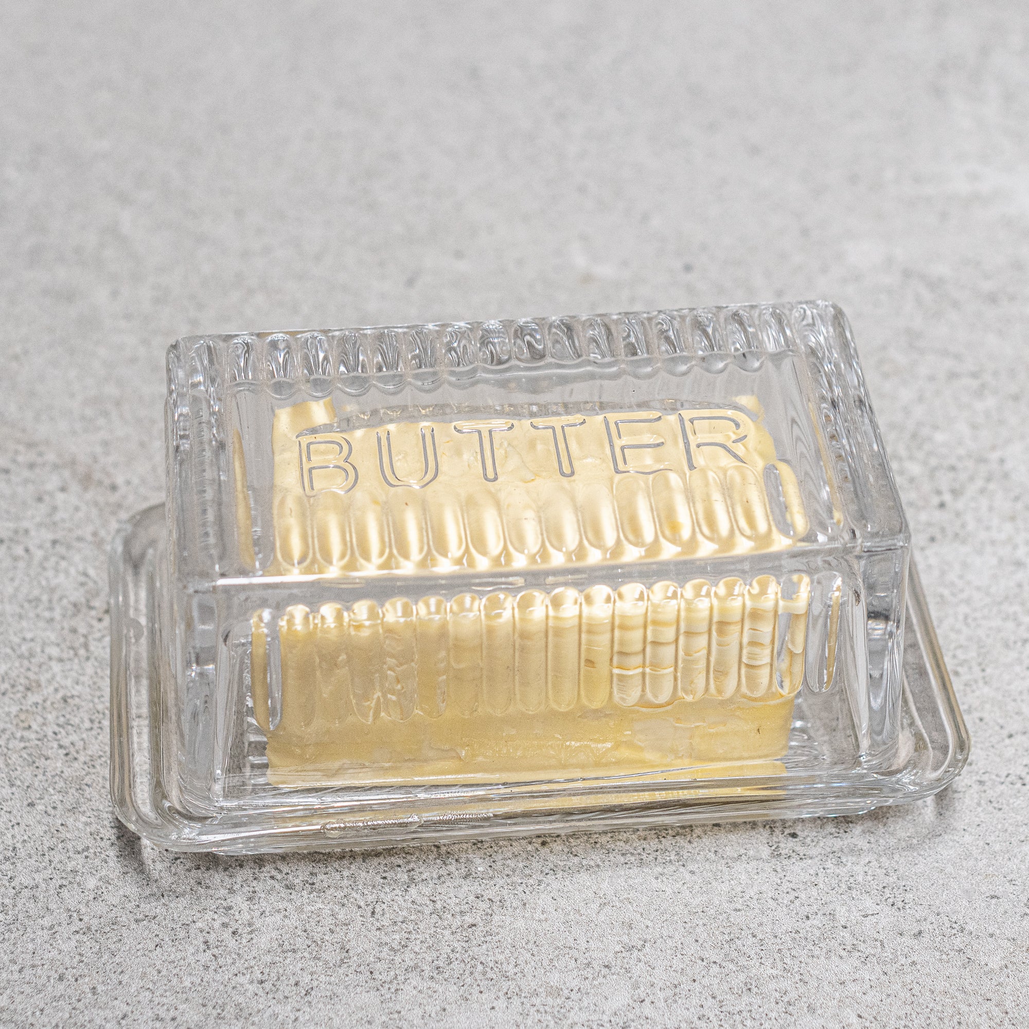Vintage design glass butter dish, featuring elegant detailing and a classic lid, perfect for keeping butter fresh while adding a nostalgic touch to your table setting