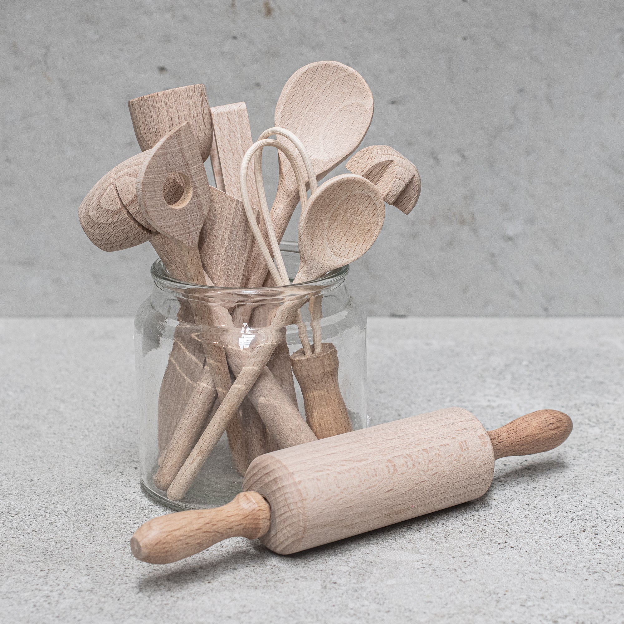 Children's wooden German-made cookset, crafted from durable, natural wood, featuring miniature kitchen tools like a spoon, whisk and tongs, designed for imaginative play and budding chefs.