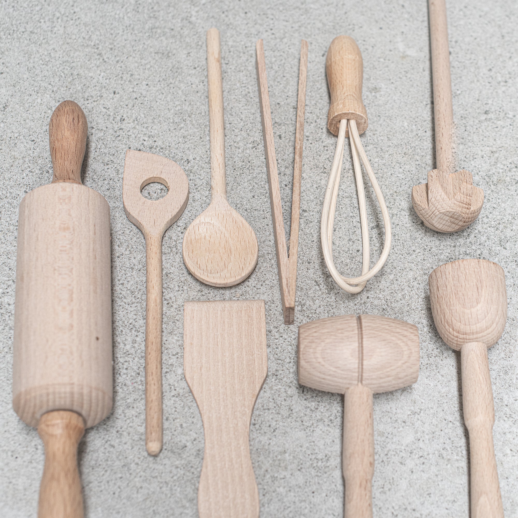 Children's wooden German-made cookset, crafted from durable, natural wood, featuring miniature kitchen tools like a spoon, whisk and tongs, designed for imaginative play and budding chefs.