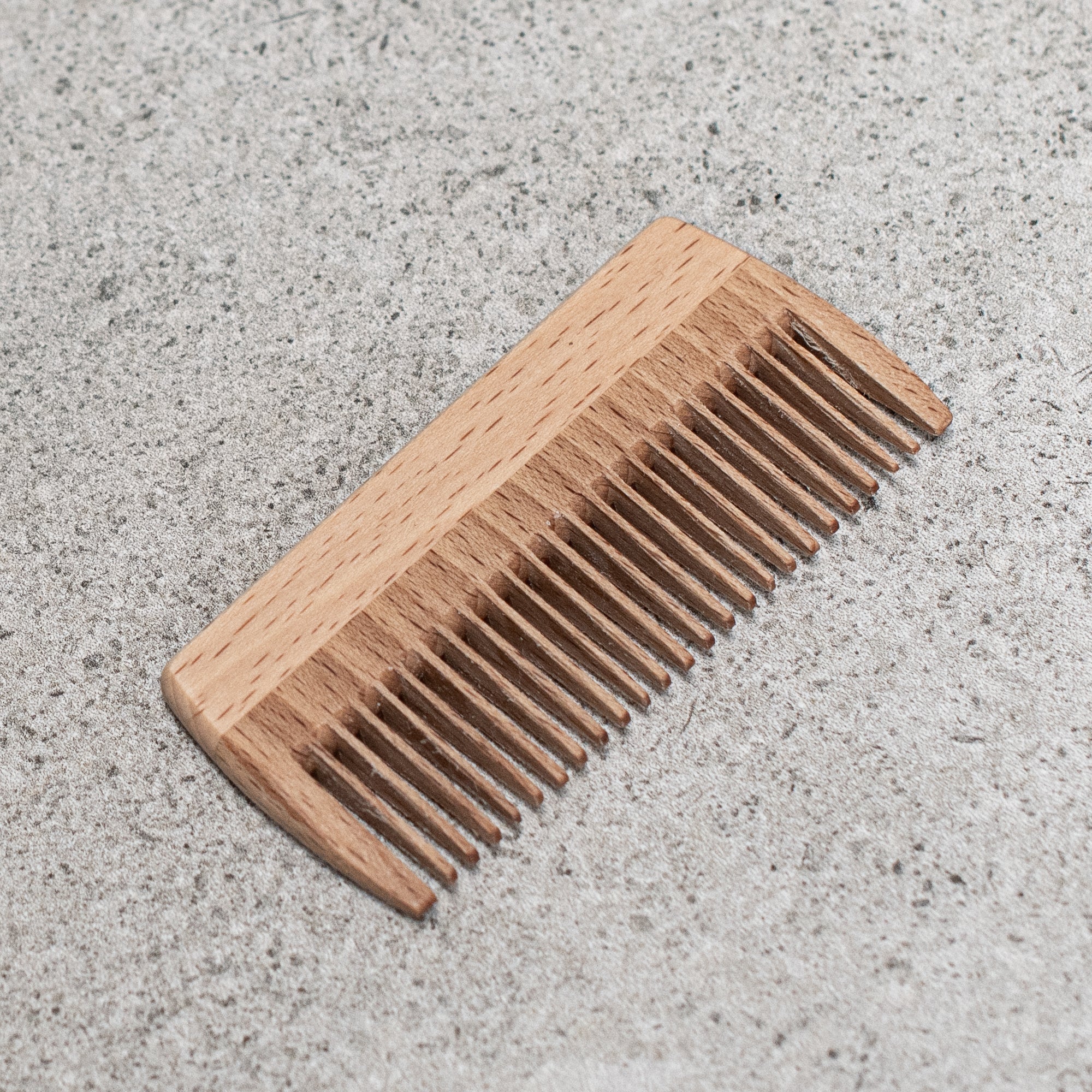 Compact beard comb with fine and wide teeth, crafted from durable beechwood to detangle and smooth facial hair with ease