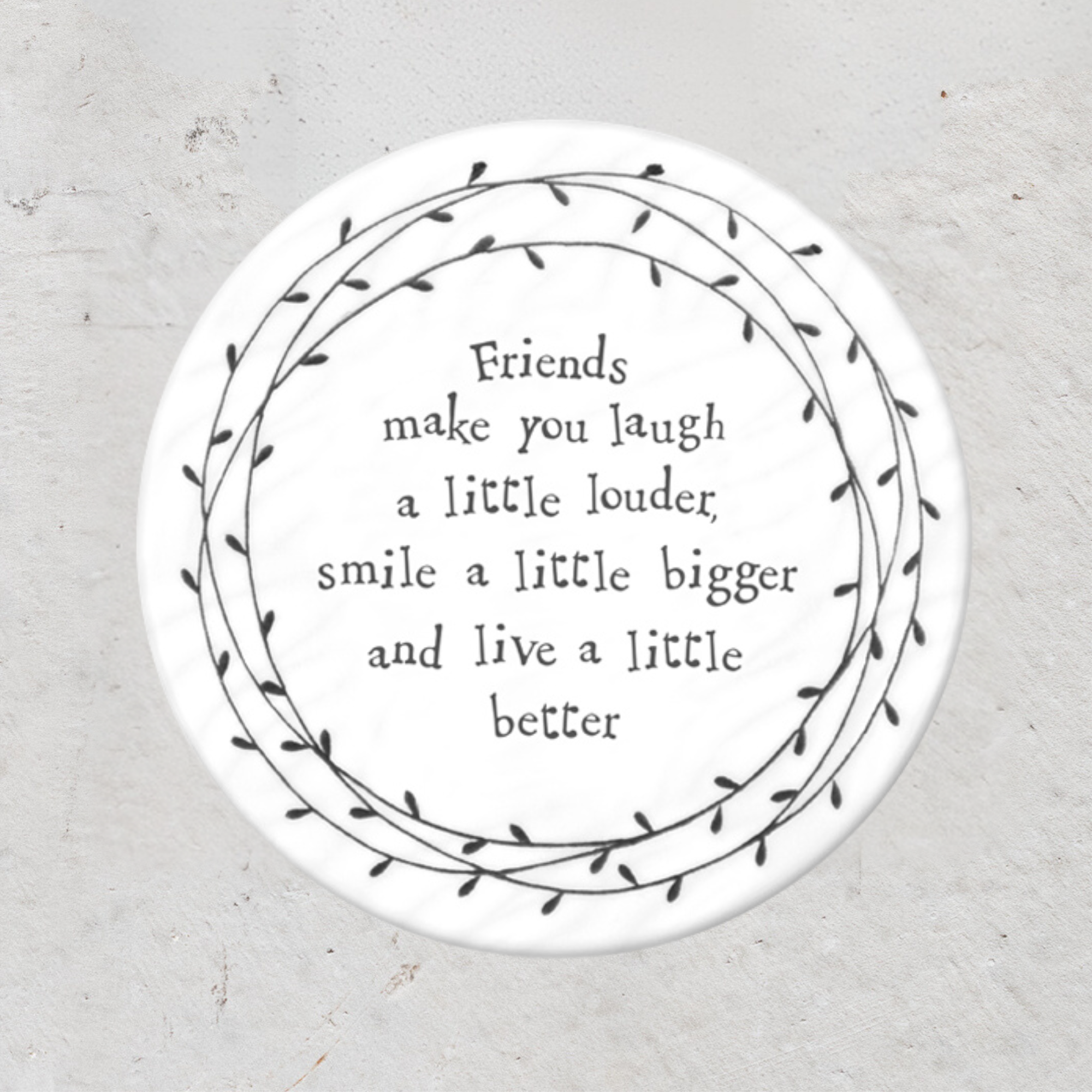 A round porcelain coaster with a black floral pattern and text that reads 'Hope you have an amazing day!' on a textured background.