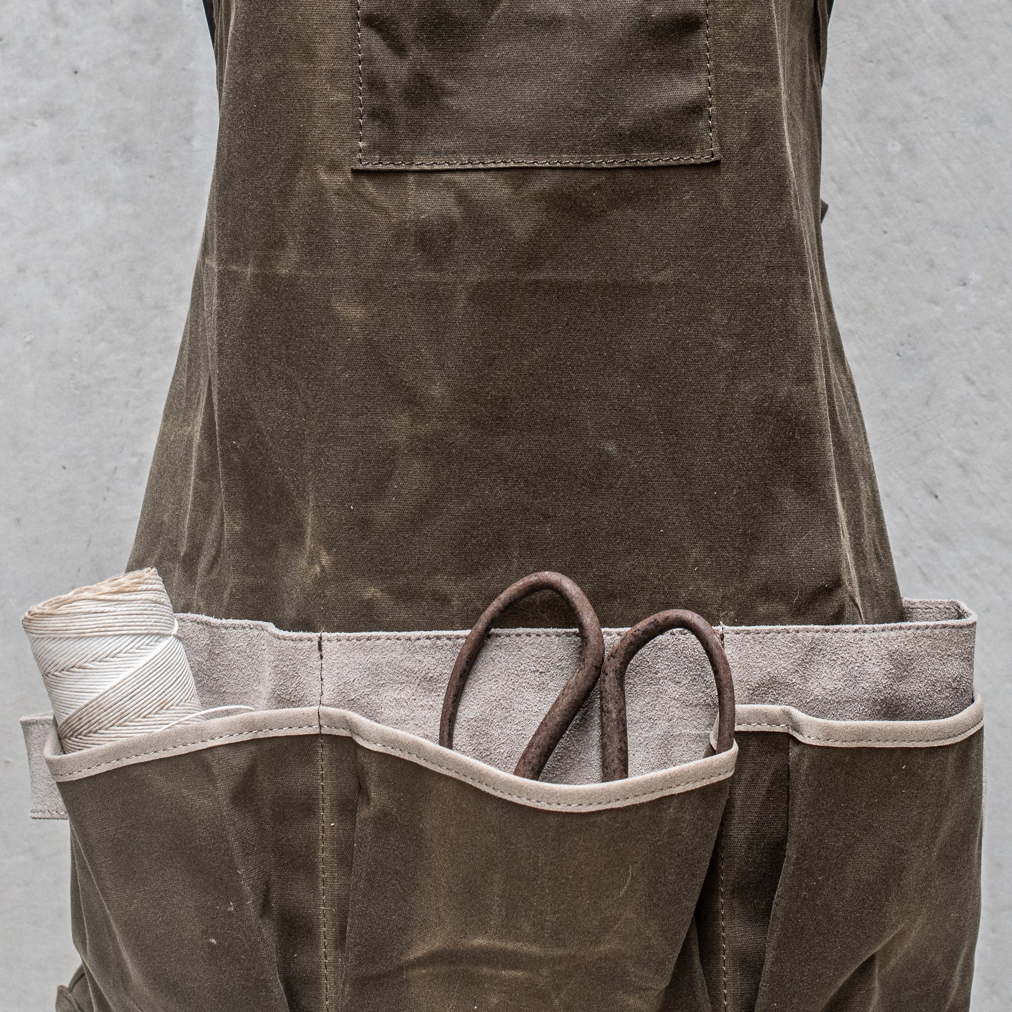 Waxed Canvas and Suede Apron by Heaven in Earth, designed for durability and style. Featuring a rugged waxed canvas body with soft suede accents, this apron is perfect for cooking, gardening, or crafting. Its adjustable straps and functional pockets make it as practical as it is fashionable, offering protection while adding a rustic, earthy touch to any task