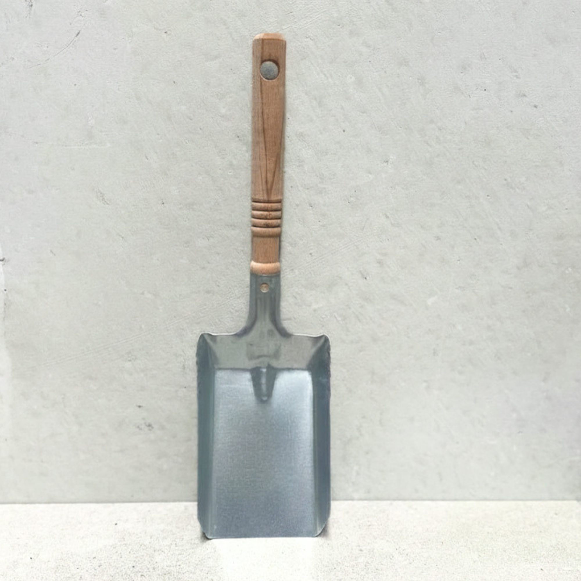 Galvanised steel coal shovel with turned wooden handle for fireplaces and wood heaters.