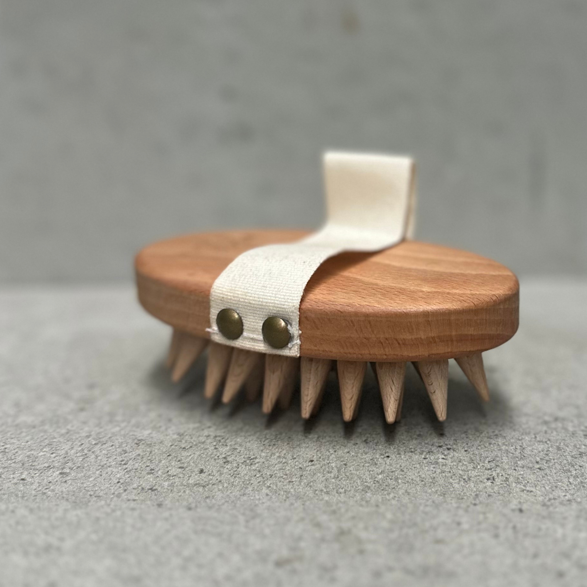 Wooden fascia massage brush with rounded wooden massage points and cotton hand strap, designed for deep tissue massage and myofascial release.