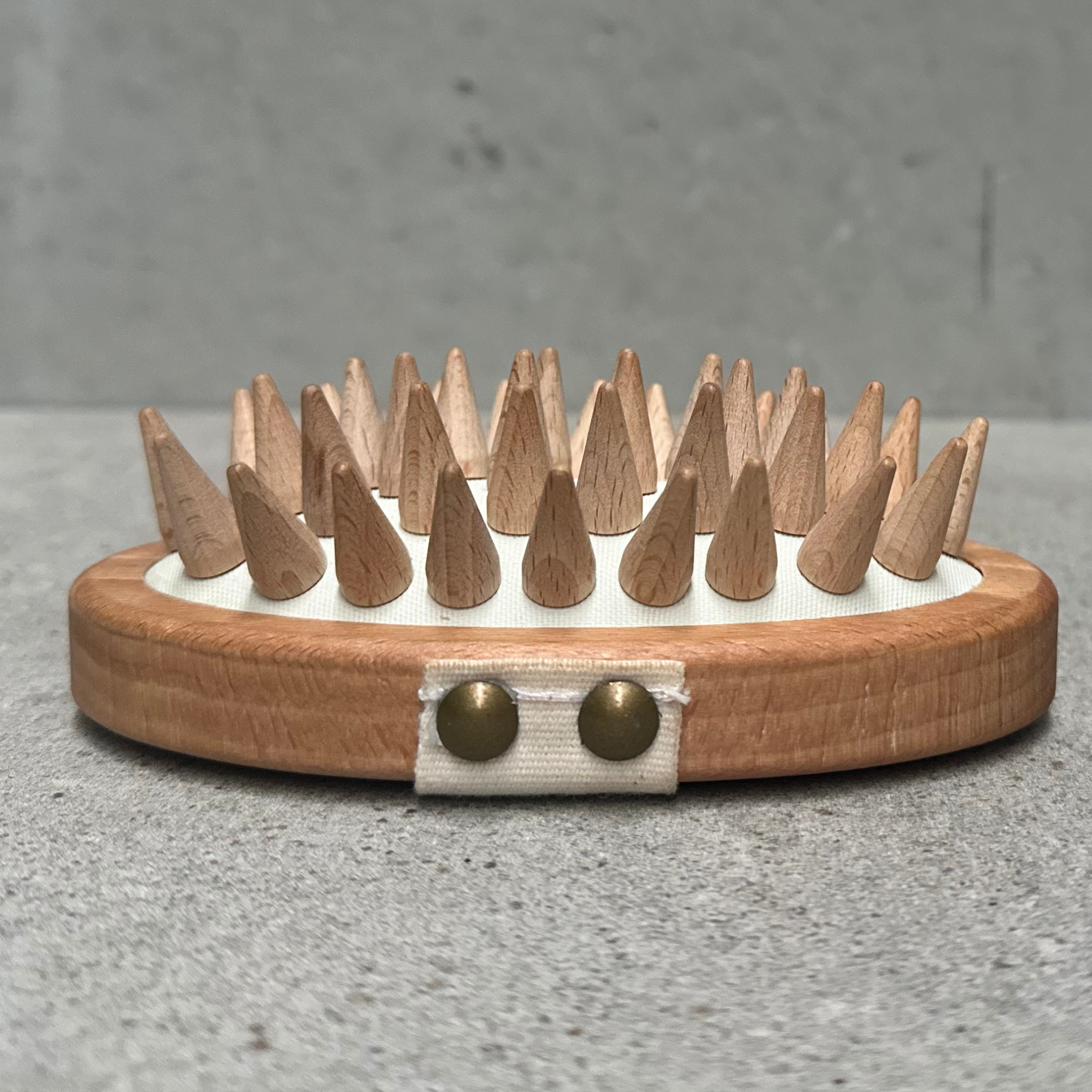 Wooden fascia massage brush with rounded wooden massage points and cotton hand strap, designed for deep tissue massage and myofascial release.