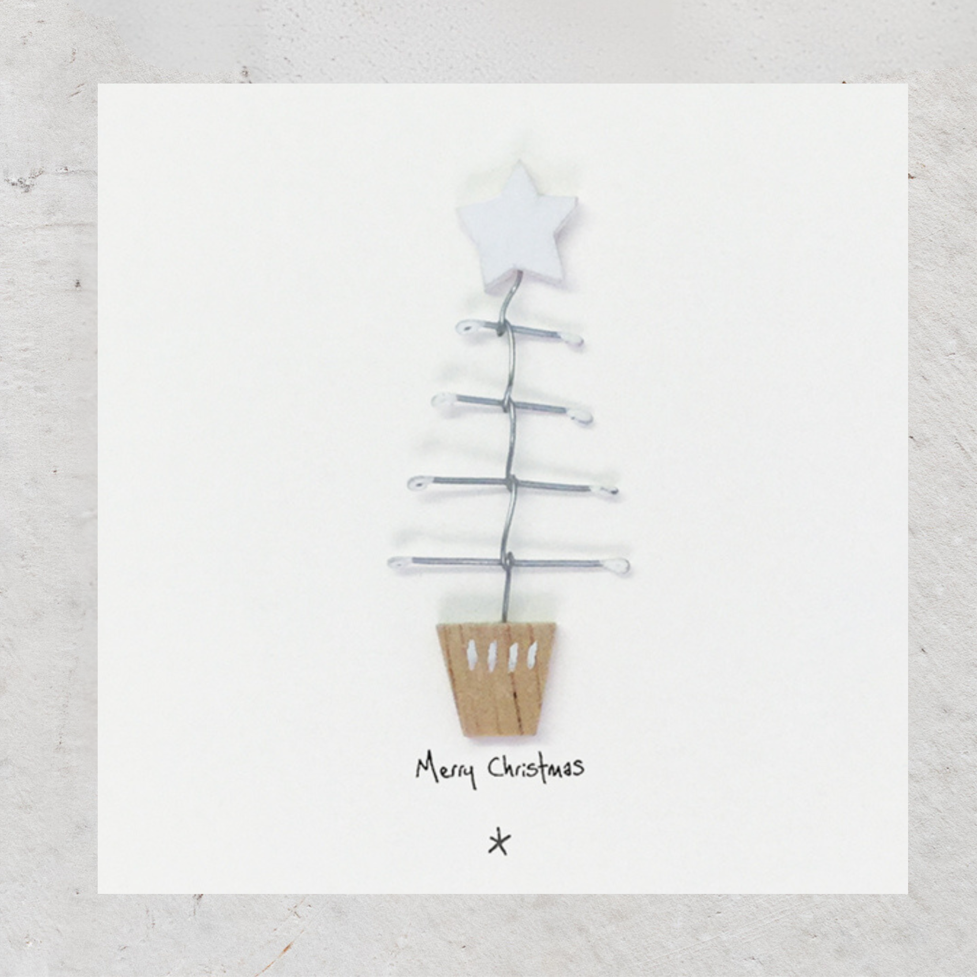Woodland Card - Merry Christmas. A contemporary card featuring a wooden Christmas tree with wire branches. Complete with grey envelope, perfect for mailing near or far, and is packaged in a compostable bag, an environmentally friendly