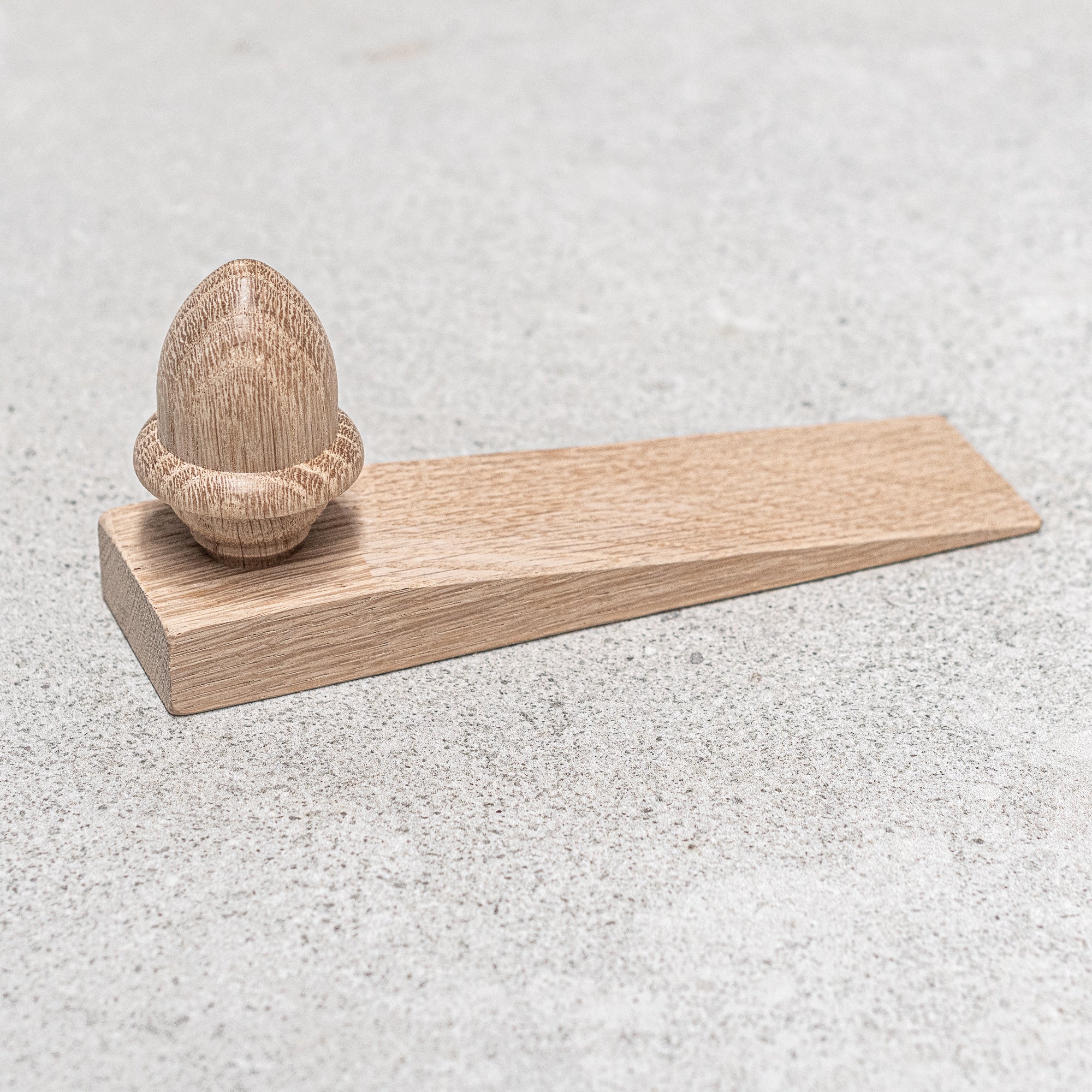 Acorn-shaped oak door wedge, crafted from solid wood with a rustic finish, designed to securely hold doors in place with a charming, natural touch