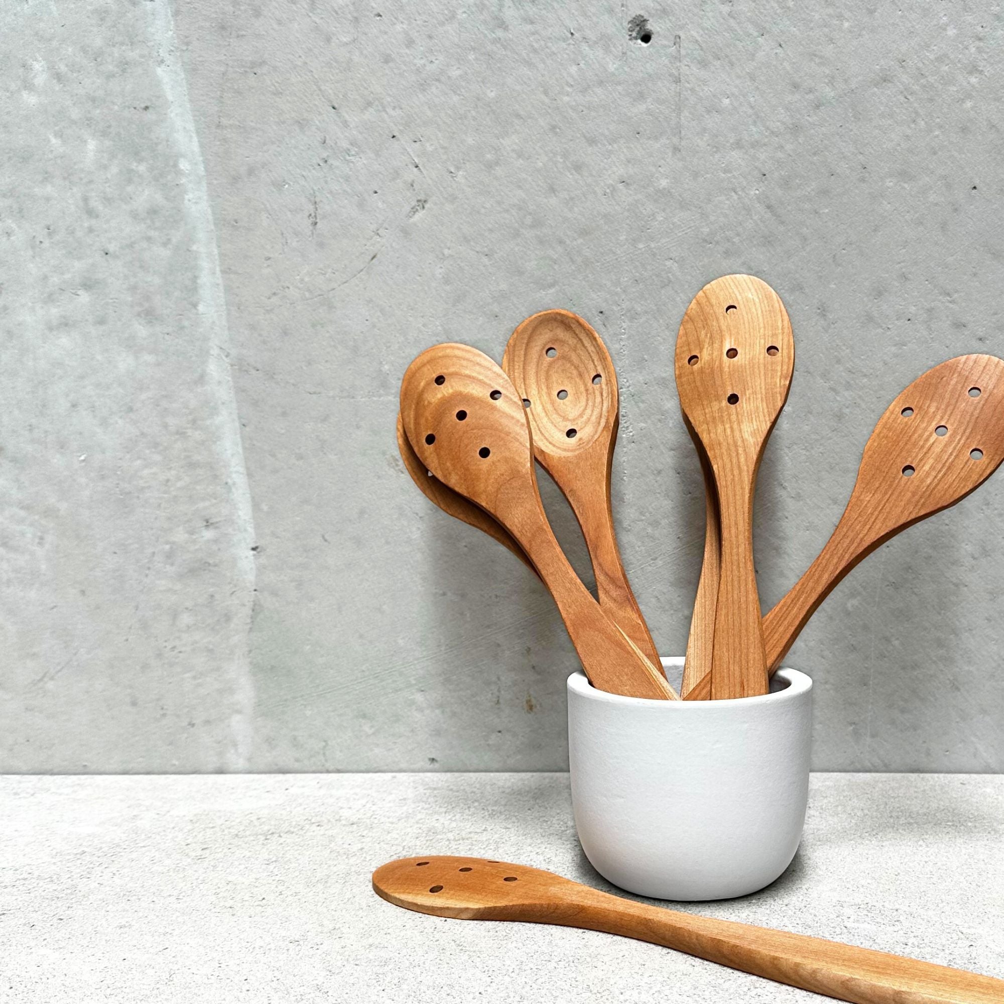 German-made eco cherrywood holed spoon, crafted from sustainably sourced cherrywood with a unique hole design, perfect for stirring, serving, and draining liquids with a natural, eco-friendly touch