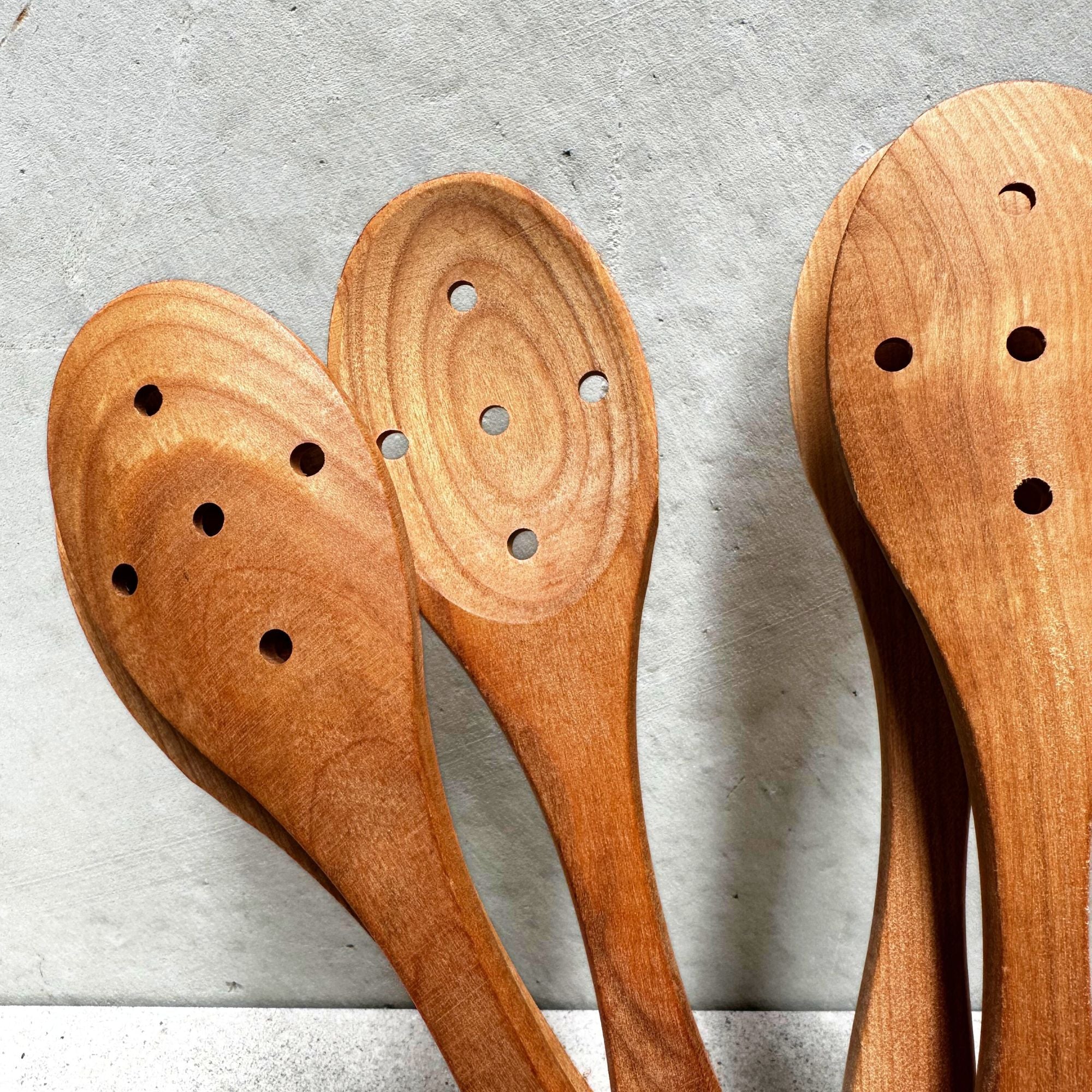 German-made eco cherrywood holed spoon, crafted from sustainably sourced cherrywood with a unique hole design, perfect for stirring, serving, and draining liquids with a natural, eco-friendly touch