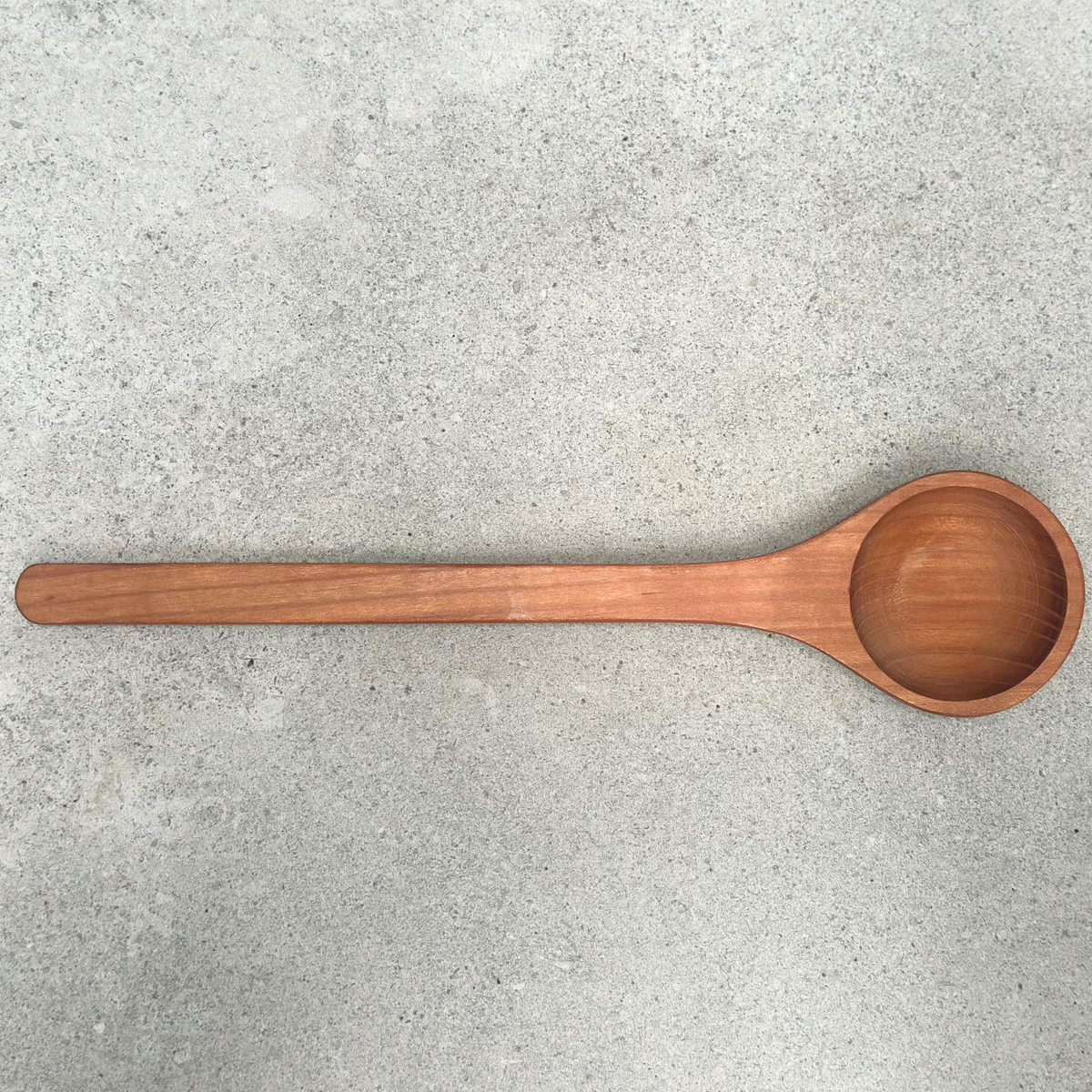 Deep cherrywood wooden cooking spoon with long handle and rounded serving bowl, handcrafted in Germany.

