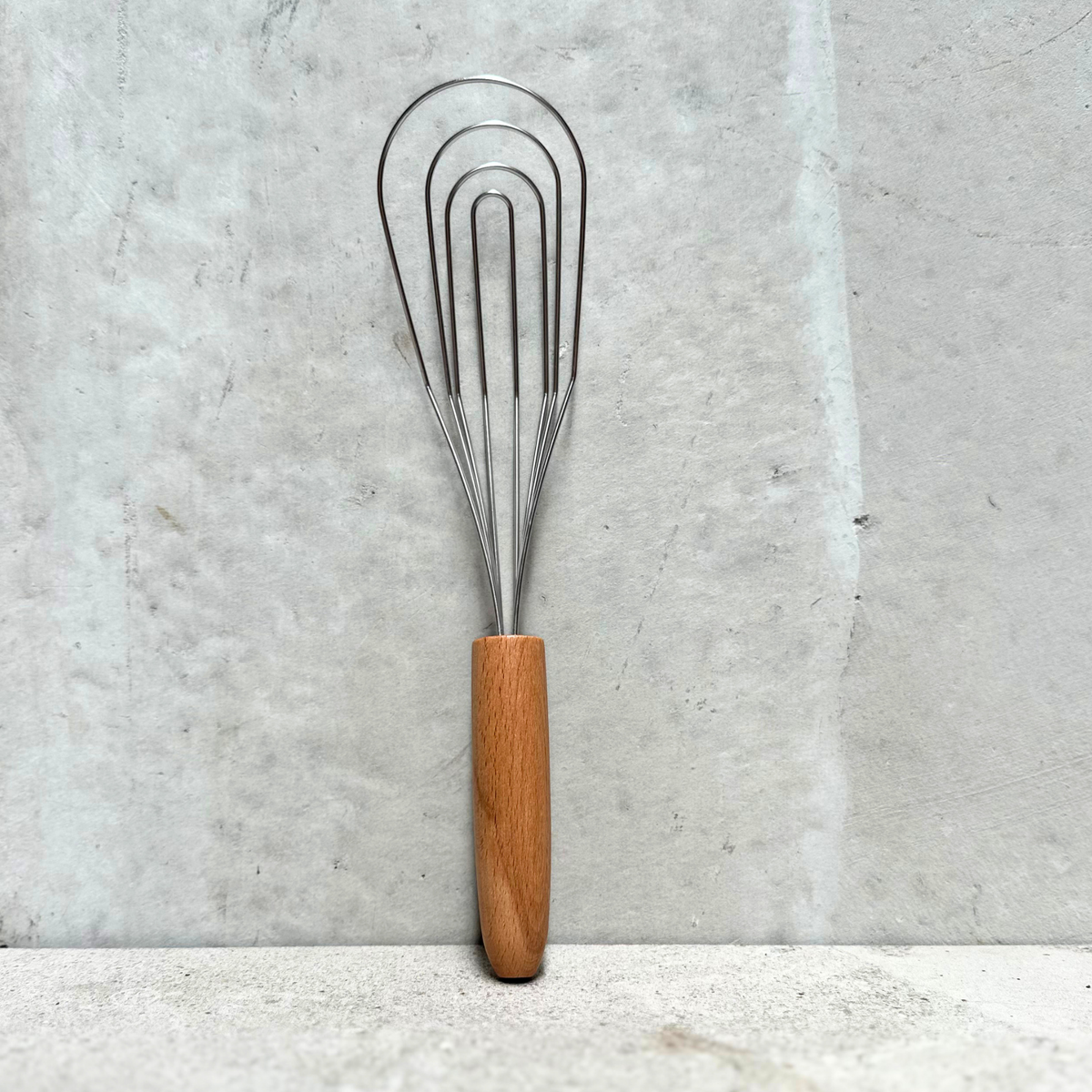 Flat-head stainless steel whisk with FSC® beechwood handle, designed for smooth mixing and sauce making, made in Germany.