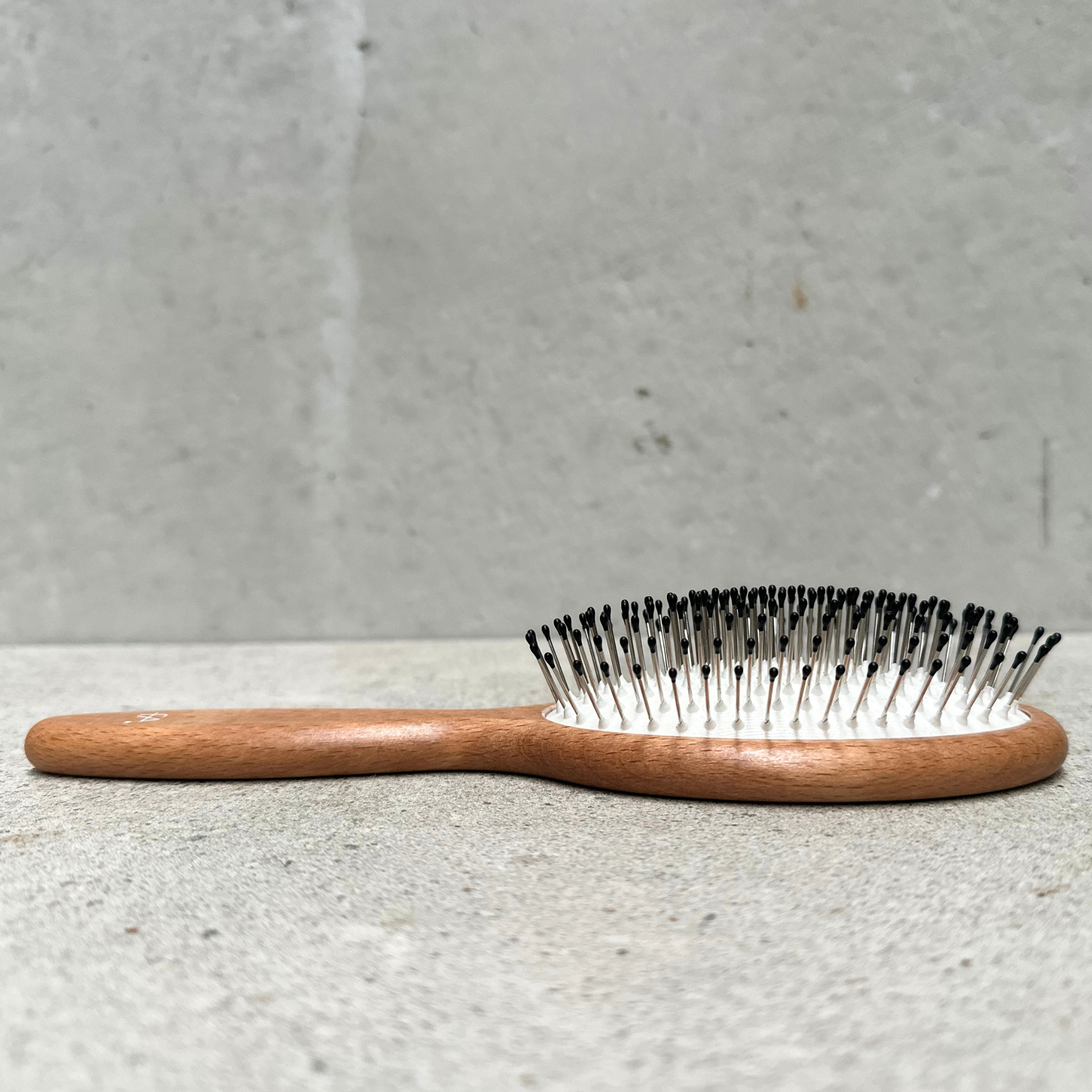 Oval vegan detangling hair brush with flexible rounded steel pins and beechwood handle for normal hair by Faller Germany.