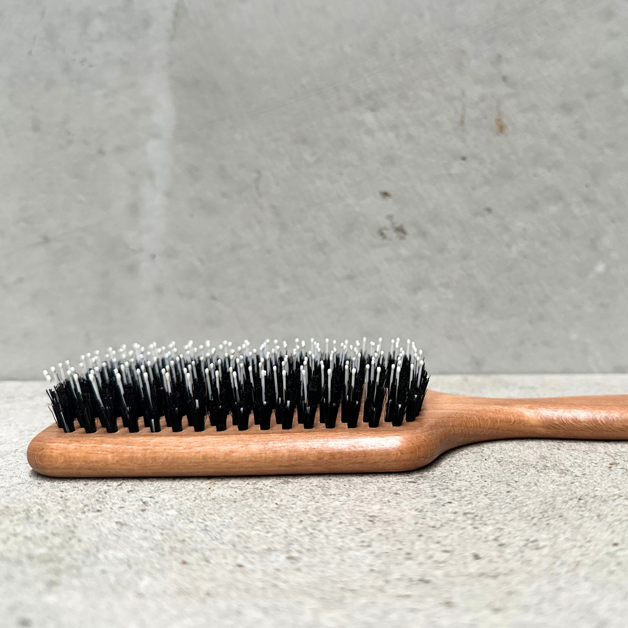 Paddle hair brush with natural bristles, rounded nylon pins and beechwood handle for curly and frizzy hair by Faller Germany.